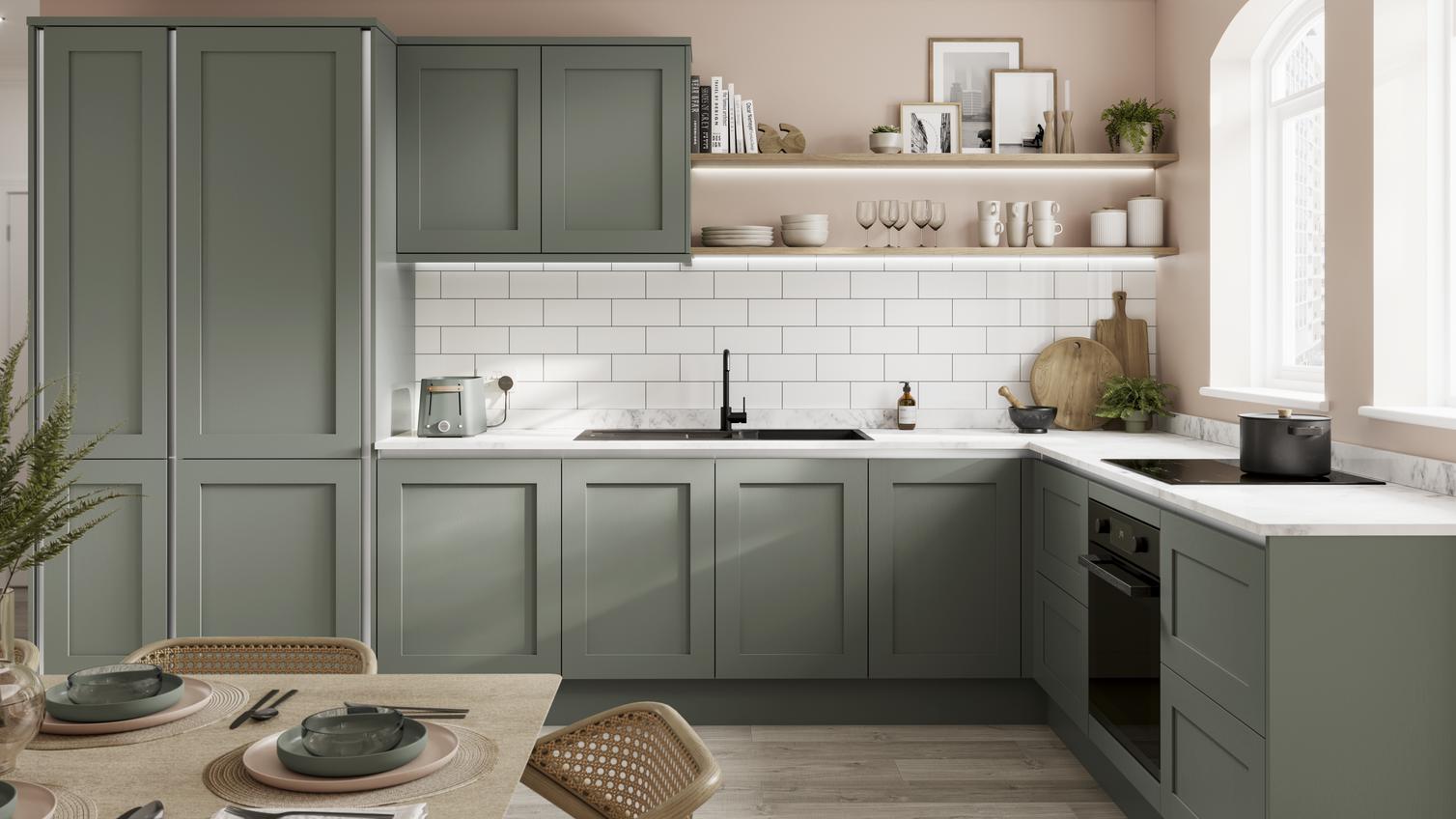 A reed green handleless kitchen idea in an l-shaped layout, with white worktops, black fixtures, and white backboard tiles.